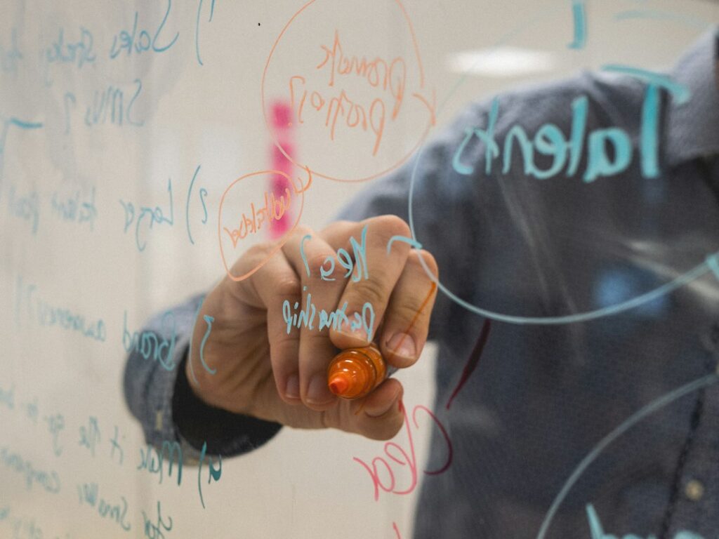 Person skizziert Diagramme auf einem Whiteboard, um eine Entscheidung im Betrieb zu strukturieren